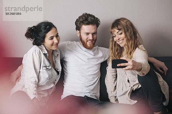 Junge Freunde nehmen Selfie durch Smartphone im Wohnzimmer mit