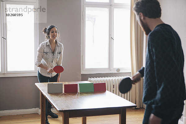 Junge Frau beim Tischtennisspielen mit Mann zu Hause