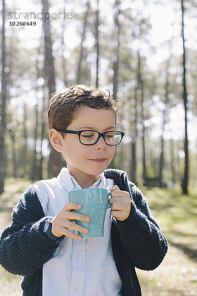 Junge mit Kaffeetasse im Wald