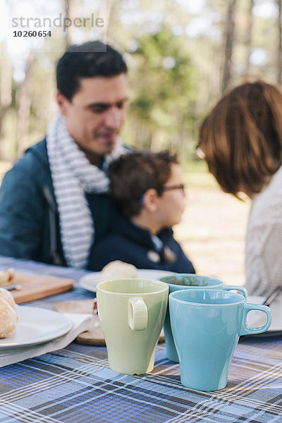 Familie sitzt am Frühstückstisch im Wald