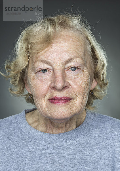 Nahaufnahme des Porträts einer älteren Frau vor grauem Hintergrund