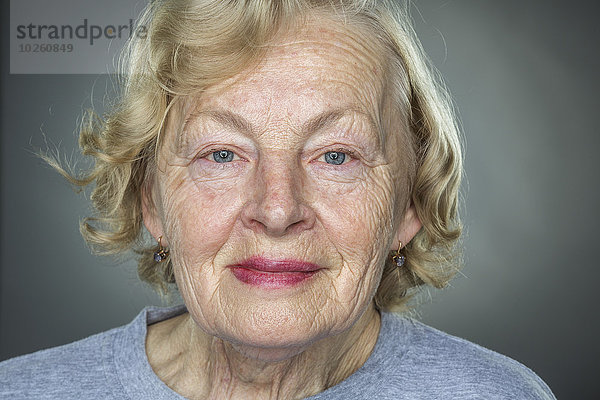 Nahaufnahme der lächelnden Seniorin vor grauem Hintergrund