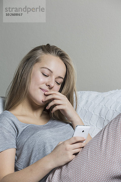 Teenager Mädchen mit Smartphone auf dem Sofa zu Hause