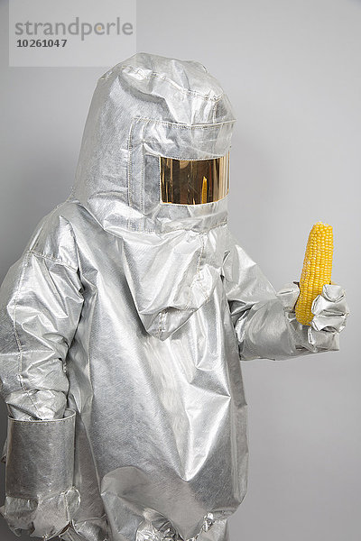 Eine Person in einem Strahlenschutzanzug  die einen Maiskolben hält.