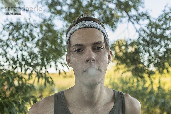 Porträt eines jungen Mannes  der im Freien raucht