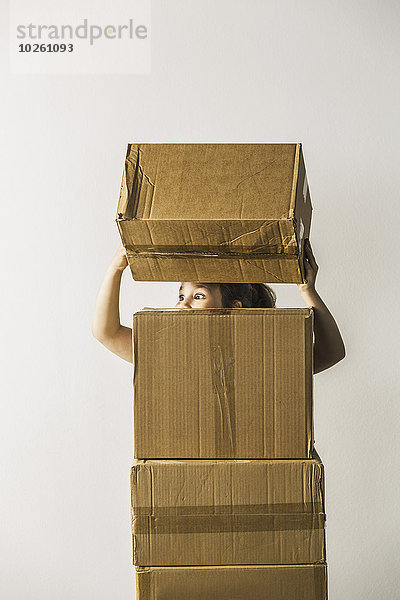 Mädchen schaut weg und stapelt Boxen vor weißem Hintergrund