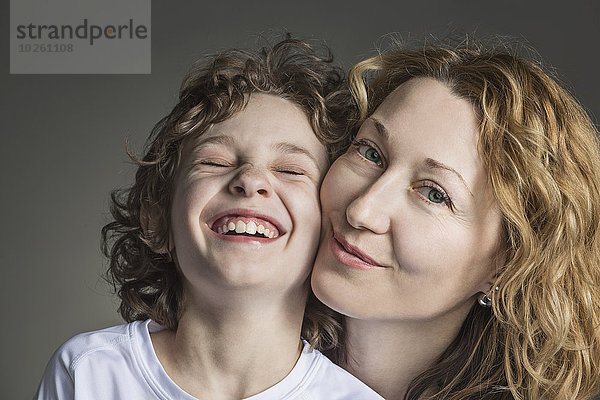 Nahaufnahme von Mutter mit fröhlichem Sohn über grauem Hintergrund