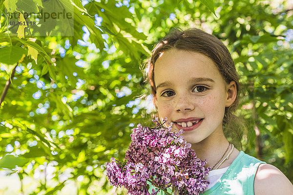 Porträt eines glücklichen Mädchens mit lila Blumen im Freien