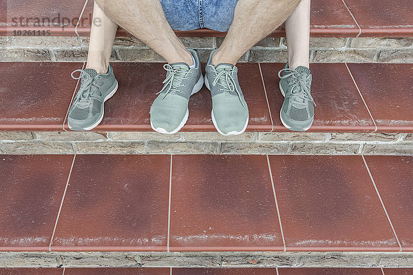 Niedriger Teil des jungen Paares auf der Treppe sitzend