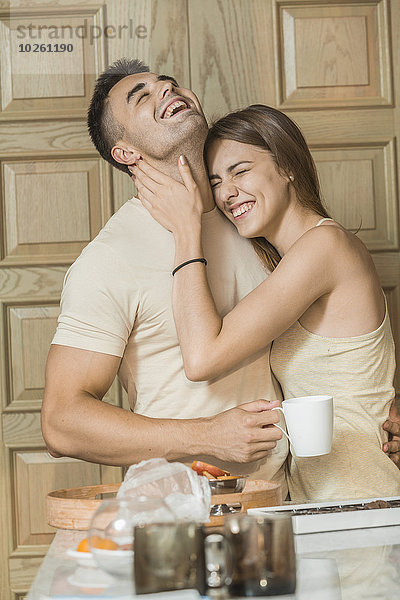 Fröhliches junges Paar  das sich in der Küche umarmt