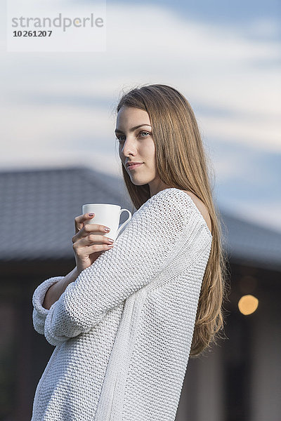 Schöne junge Frau mit Kaffeetasse im Freien