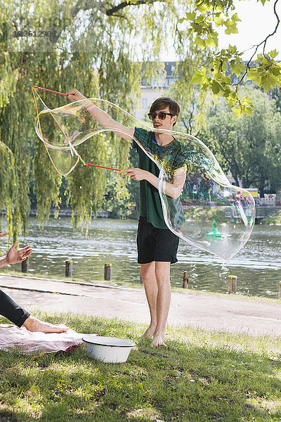 Junger Mann macht große Blase im Park