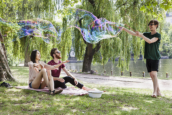 Glückliche Freunde genießen mit großer Blase im Park