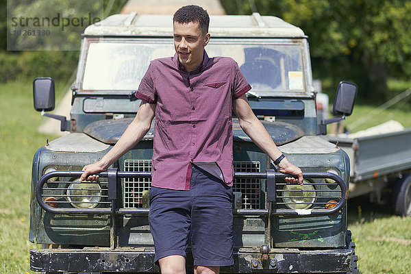 Junger Mann  der sich im Park auf einen Lastwagen stützt.