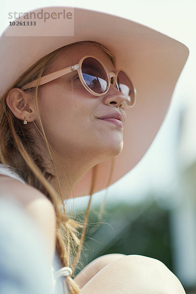 Flachwinkelansicht der jungen Frau mit Sonnenbrille und Hut