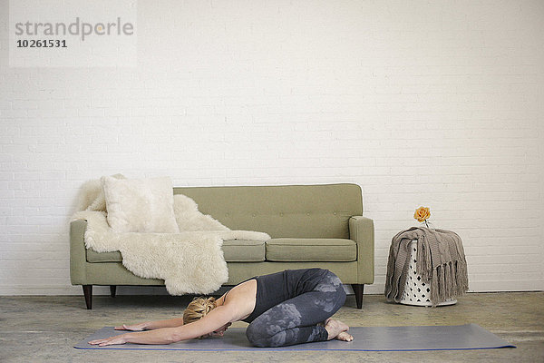 Frau kniend schwarz frontal Yoga Turnanzug blond Leggins Matte