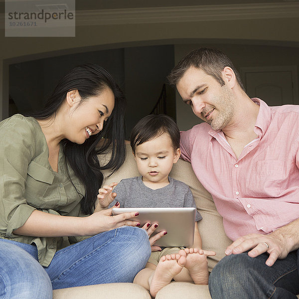 sitzend sehen Couch lächeln Sohn jung Tablet PC Seitenansicht Mann und Frau