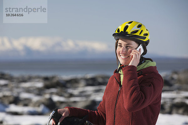 Handy stehend junge Frau junge Frauen sprechen folgen Küste Eis vorwärts Fahrrad Rad Stück gefroren
