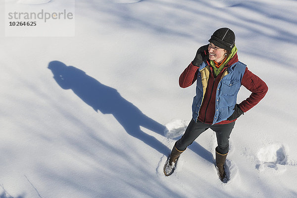 Vereinigte Staaten von Amerika USA Handy junge Frau junge Frauen Winter sprechen lächeln Hut Handschuh Schneewehe Kleidung