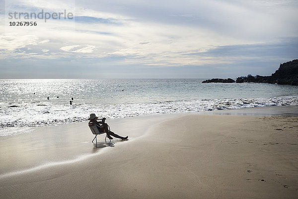 Frau sitzend Buch Stuhl Ecke Ecken Strand Sonnenuntergang Mexiko Taschenbuch vorlesen