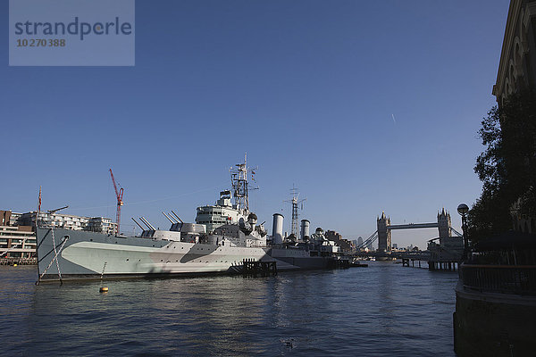 Kriegsschiff HMS Belfast  angedockt an der Themse und Teil des Imperialen Kriegsmuseums  Blick auf die Tower Bridge und Canary Wharf in der Ferne; London  England