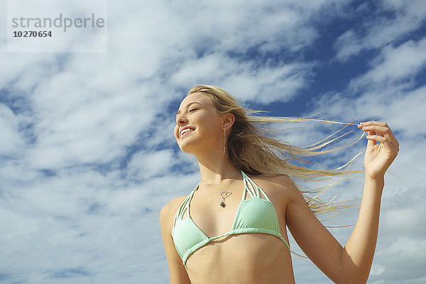 Ein Mädchen im Bikinioberteil mit langen blonden Haaren  die im Wind wehen; Kauai  Hawaii  Vereinigte Staaten von Amerika