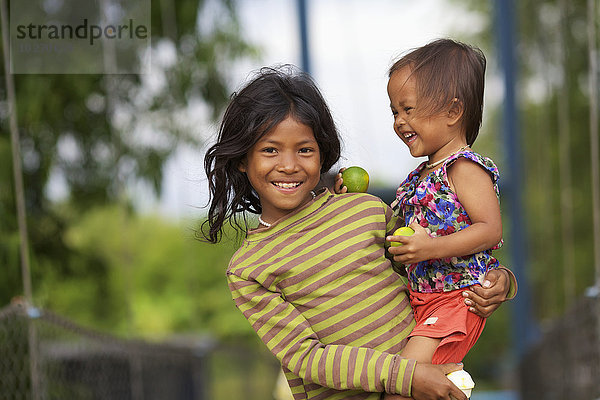 Ein Mädchen hält seine junge Cousine; Battambang  Kambodscha