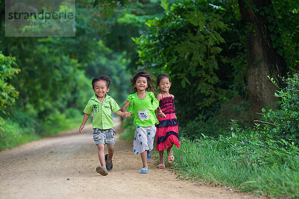 Junge Kinder  die eine unbefestigte Straße hinunterlaufen; Battambang  Kambodscha