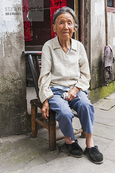 Porträt einer älteren Frau  die vor ihrem Haus in einem kleinen Dorf in der Nähe von Wuyuan sitzt; Provinz Jiangxi  China