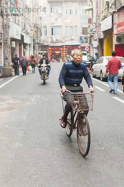 Ein älterer Mann fährt mit dem Fahrrad durch eine Straße im Stadtzentrum; Xiamen  Provinz Fujian  China