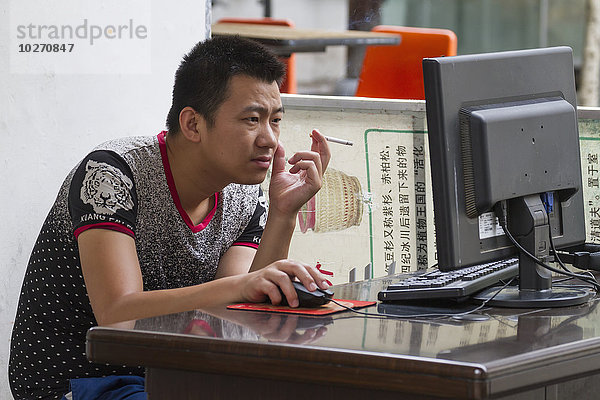 Mann rauchend vor einem Computer  Hongcun  Anhui  China