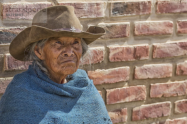 Eine ältere Frau sitzt vor einer Backsteinmauer; Toro Toro  Bolivien