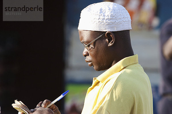 Seitenansicht eines jungen Mannes beim Tagebuchschreiben in Bamako  Mali