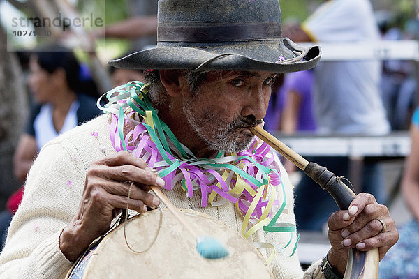 Mann spielt eine Erque  während er auf einer Caja in der Entrada De Comadritas Parade während des Carnaval Chapaco  Tarija  Bolivien trommelt