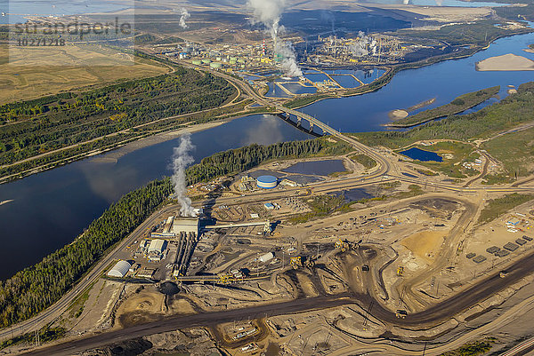 Weitwinkel-Luftaufnahme einer Ölsandmine nördlich von Fort McMurray  Alberta; die industrielle Produktionsraffinerie befindet sich im oberen Teil des Bildes  der untere Teil ist das unbearbeitete Minengelände  auf dem das Bitumen am Ufer des Athabasca River gesammelt wird; Fort McMurray  Alberta  Kanada