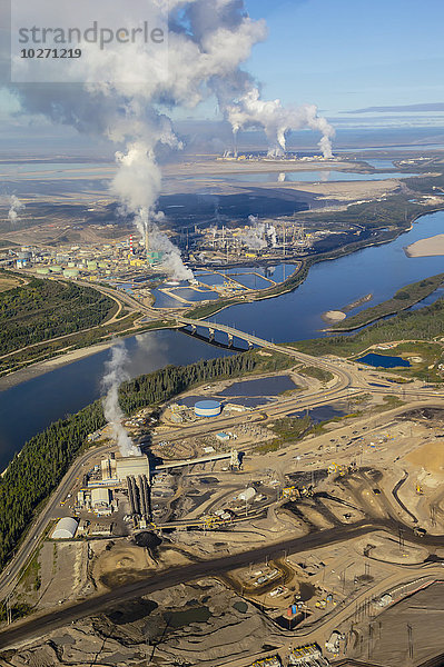 Luftaufnahme einer Ölsandmine nördlich von Fort McMurray  Alberta; die industrielle Produktionsraffinerie befindet sich im oberen Teil des Bildes  der untere Teil ist das unbearbeitete Minengelände  auf dem das Bitumen am Ufer des Athabasca River gesammelt wird; Fort McMurray  Alberta  Kanada