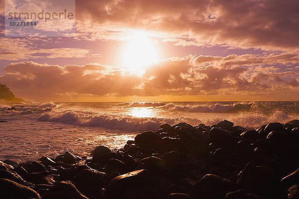 Sonnenaufgang und Wellen  die gegen die Felsen schlagen  Kealia Beach; Kauai  Hawaii  Vereinigte Staaten von Amerika'.