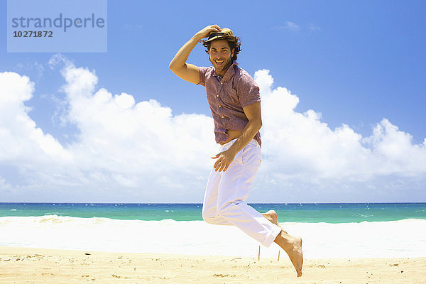 Mann  der am Strand in die Luft springt; Kealia  Kauai  Hawaii  Vereinigte Staaten von Amerika'.