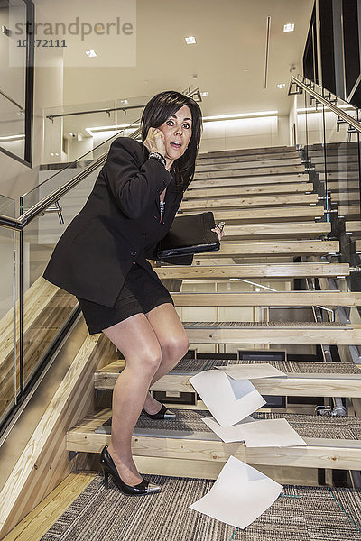 Professionelle Geschäftsfrau lässt ihre Papiere auf der Treppe fallen und schämt sich; Edmonton  Alberta  Kanada'.