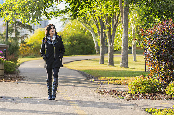 Ältere Geschäftsfrau  die im Herbst im Freien in einem Stadtpark spazieren geht; Edmonton  Alberta  Kanada'.