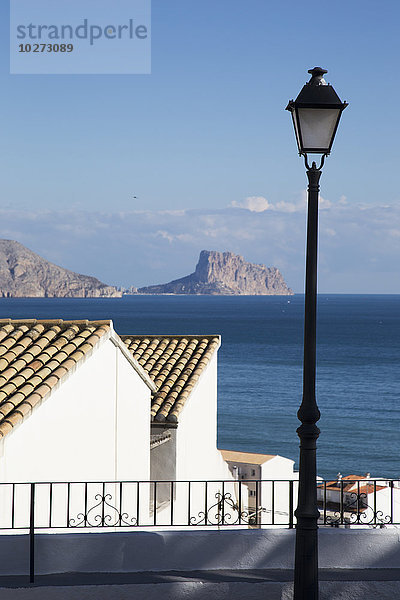 Laternenpfahl und Gebäude entlang der Küste mit einer zerklüfteten Küstenlinie in der Ferne; Altea  Spanien'.