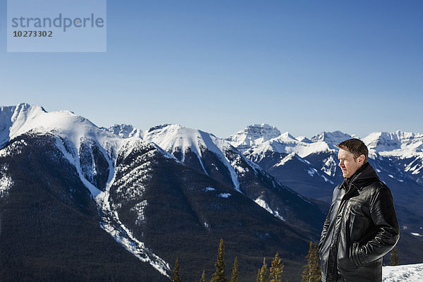 Ein Mann steht mit Blick vom Sulphur Mountain auf die kanadischen Rockies im Winter; Banff  Alberta  Kanada'.