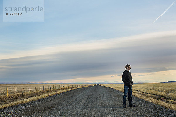 Mann steht auf einer Landstraße; Claresholm  Alberta  Kanada'.