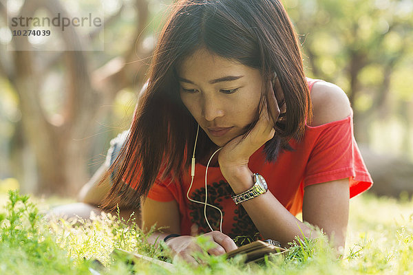Chinesisches Mädchen liest ein Buch und hört Musik; Xiamen  Provinz Fujian  China'.