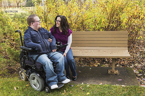 Behinderter Mann im Gespräch mit seiner Frau auf einer Parkbank im Herbst; Edmonton  Alberta  Kanada'.