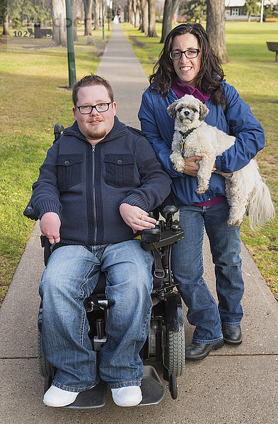 Behinderter Ehemann  seine Frau und ihr Hund posieren für ein Familienporträt in einem Park im Herbst; Edmonton  Alberta  Kanada'.