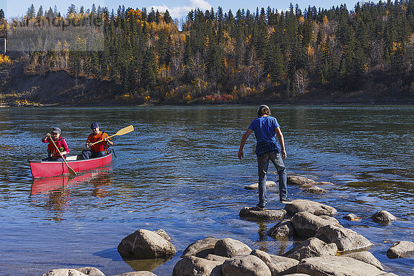 Familie auf dem North Saskatchewan River  Erwachsene fahren Kanu und der Sohn spielt auf den Felsen; Edmonton  Alberta  Kanada'.
