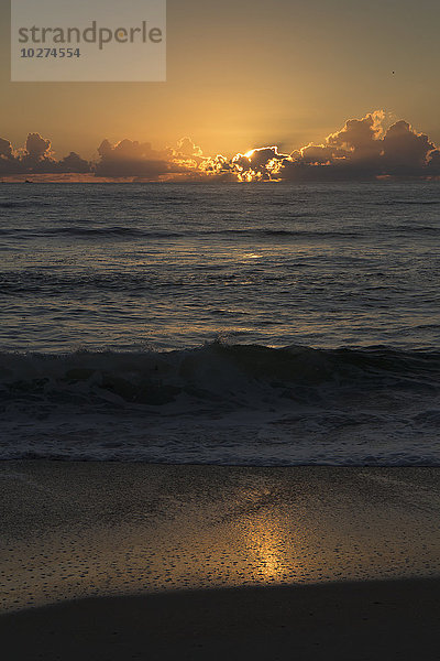 Sonnenaufgang über dem Meer mit Wellen am Ufer und dem Sonnenlicht  das sich im Sand spiegelt; Vereinigte Staaten von Amerika'.