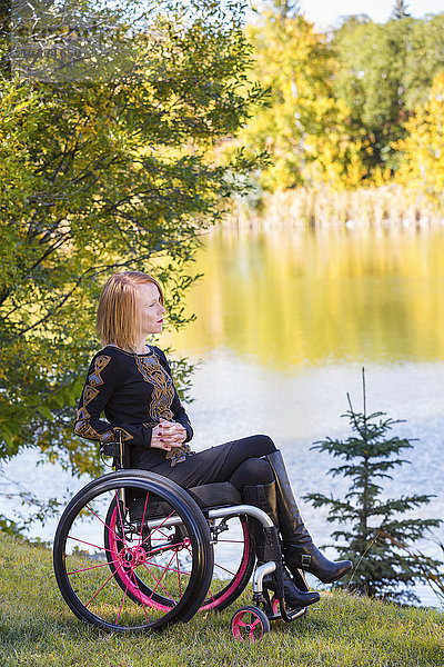 Junge behinderte Frau im Rollstuhl in einem Stadtpark im Herbst; Edmonton  Alberta  Kanada'.