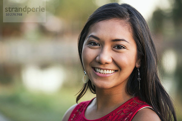 Porträt einer schönen jungen philippinischen Frau  die im Herbst in einem Stadtpark lächelt; St. Albert  Alberta  Kanada'.